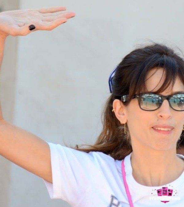 Maïwenn en lunettes de soleil et t-shirt blanc, saluant la foule