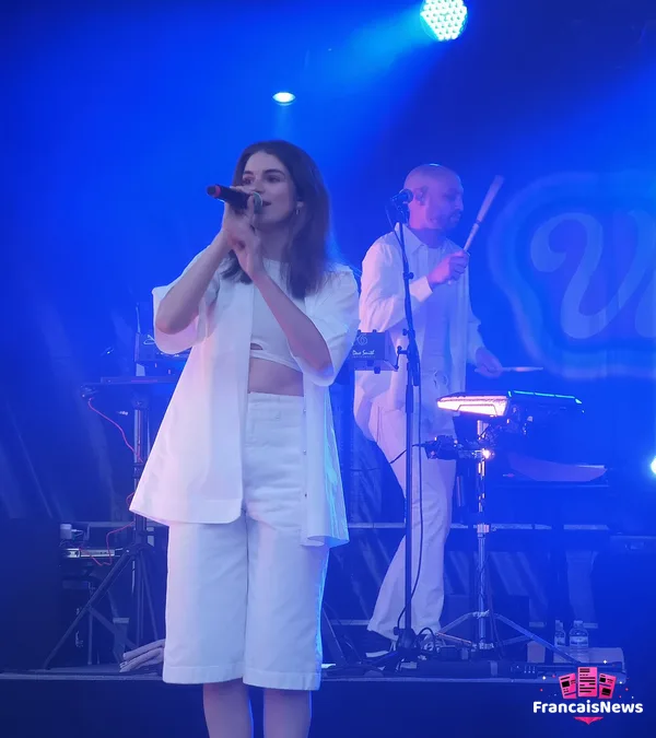 adele castillon en concert à Cergy en 2021, micro en main en tenue blanche