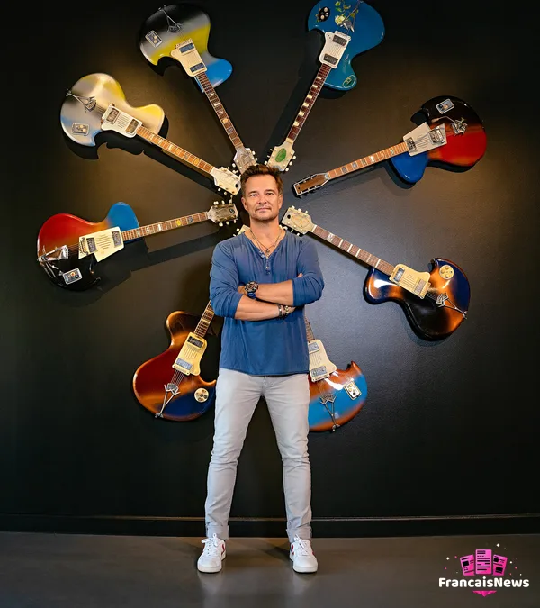 david hallyday debout devant un cercle de guitares colorées accrochées au mur