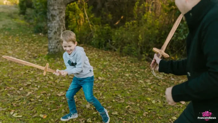 vacances de la toussaint 2026 : un père et son fils jouent aux épées en bois parmi les feuilles d'automne